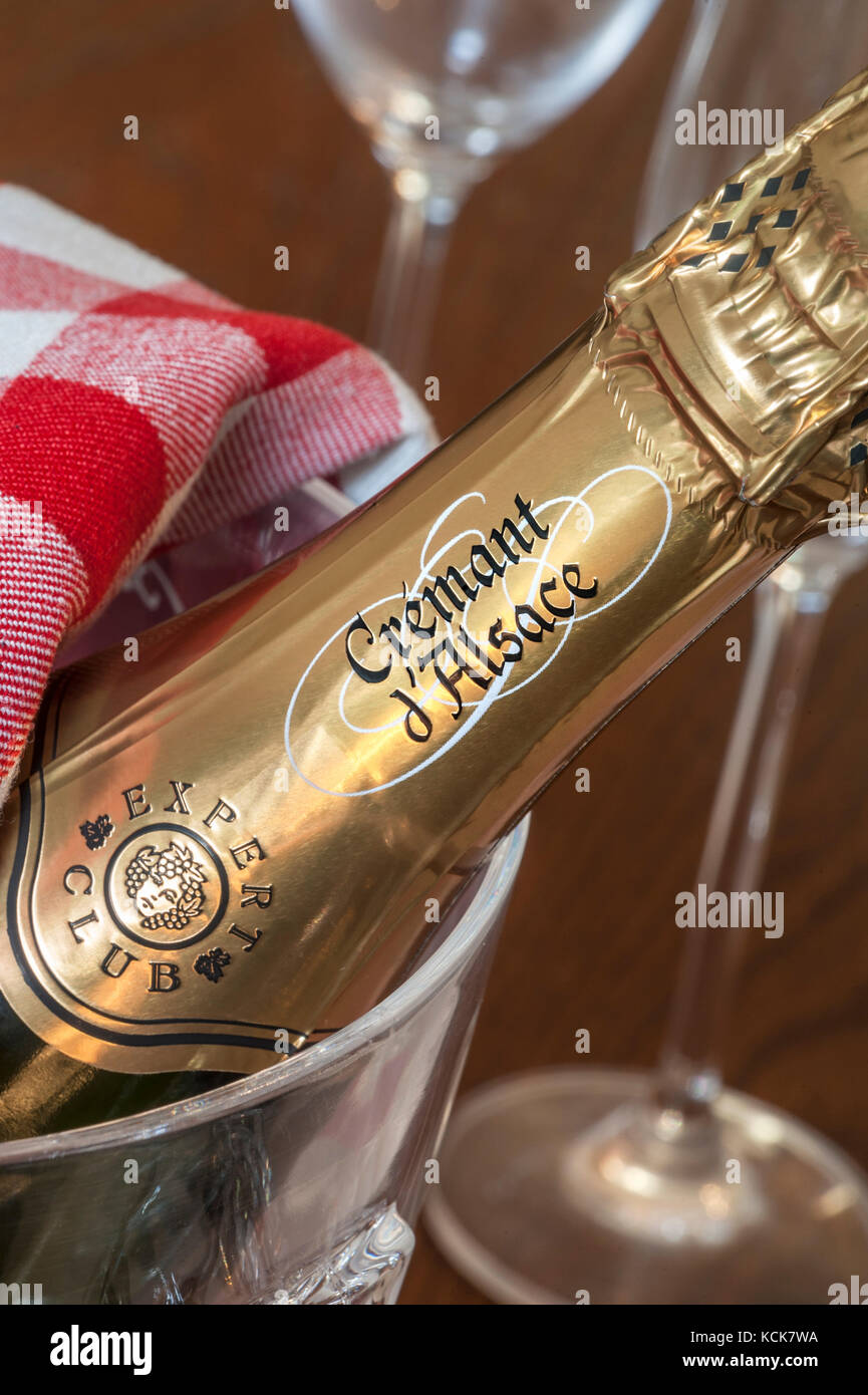Cremant d’Alsace sparkling wine bottle in ice bucket with glasses behind on formal dining table Stock Photo