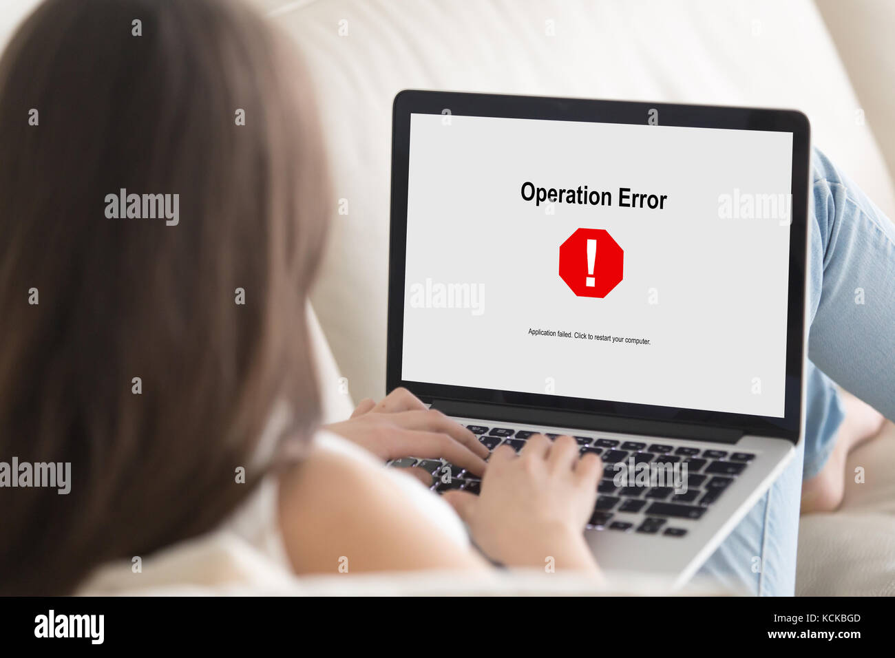 Woman lying on sofa looking at laptop screen, Operation Error message pop up. Computer crashed, software failure during web browsing, watching movie,  Stock Photo