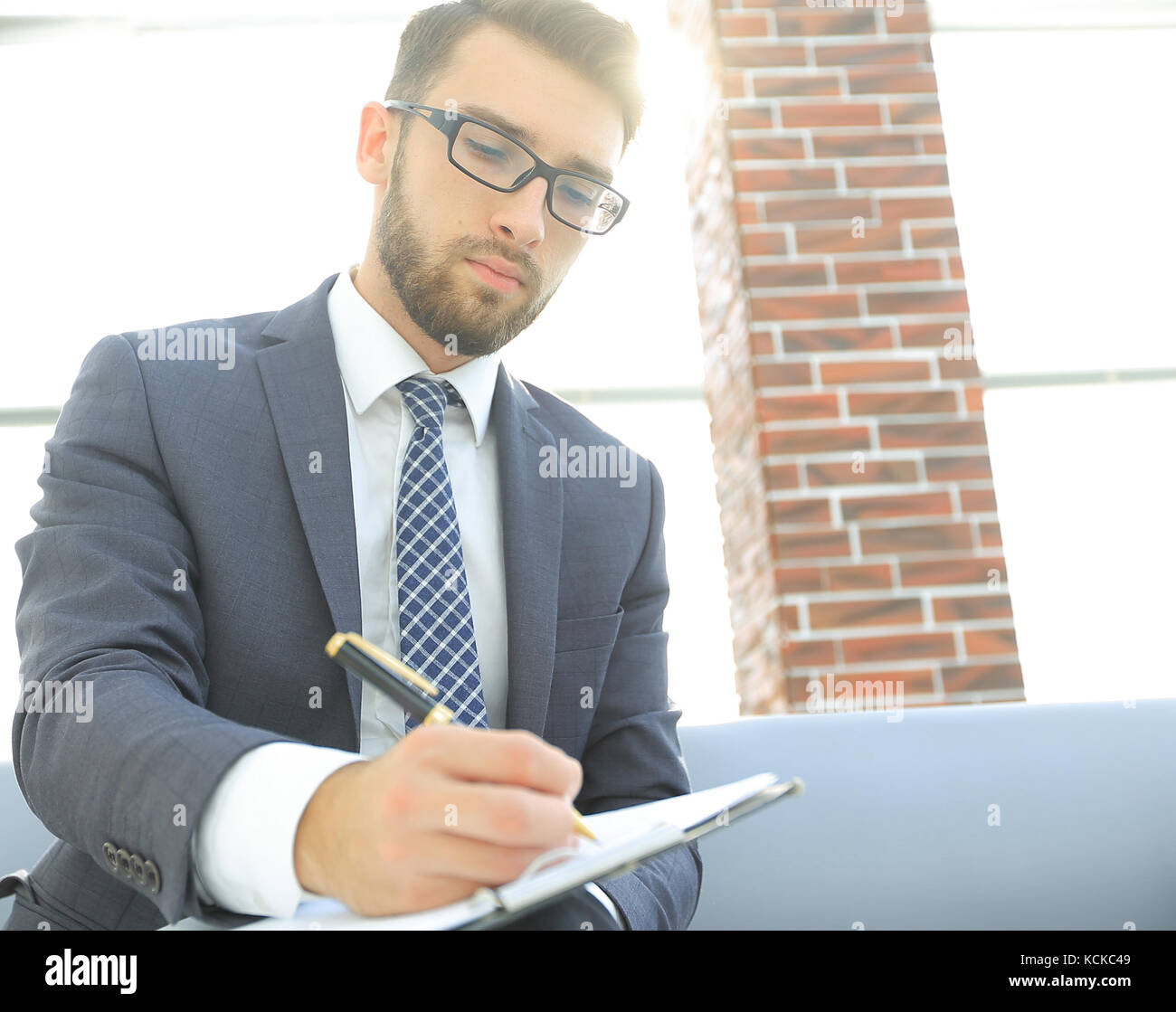 Businessman writing in a notebook in an office Stock Photo - Alamy