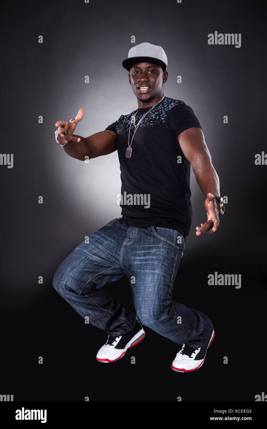 Happy African Young Man Dancing On Black Background Stock Photo