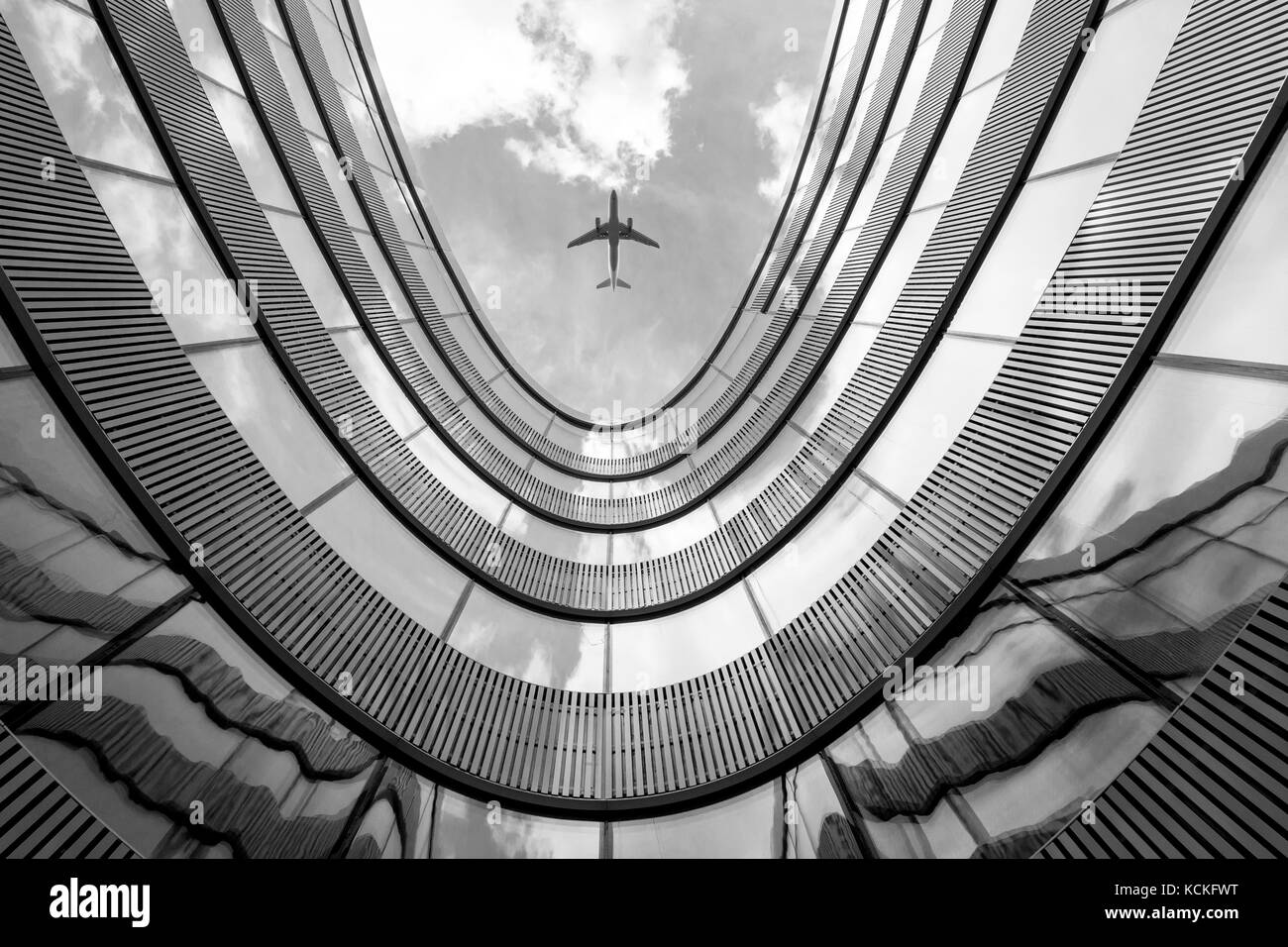 Flying airplane and modern architecture building, low angle black and white abstract looking picture Stock Photo