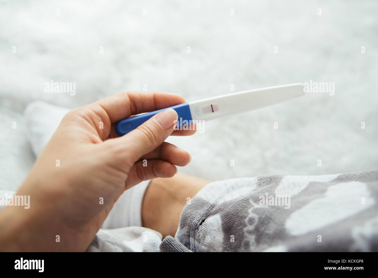 Upset woman lie sad in the bed with negative pregnancy test Stock Photo