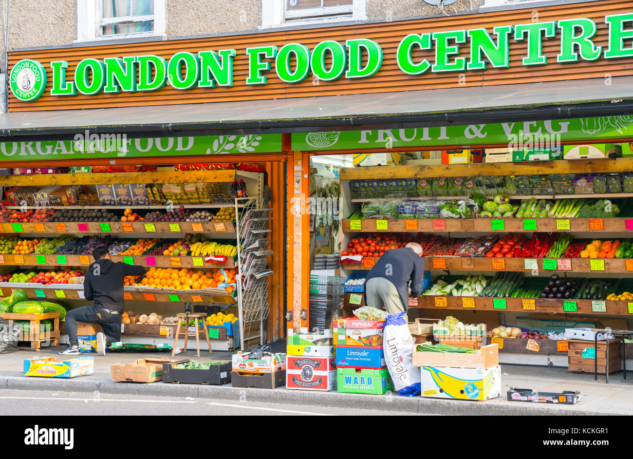 Greengrocers daily ritual stocking fruit and vegetables shelves outside