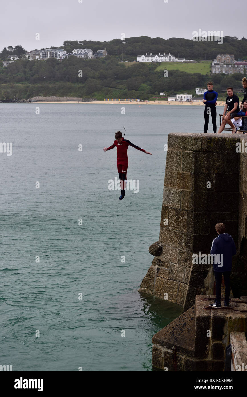 A young man jumping off the pier in St Ives harbour, Cornwall Stock