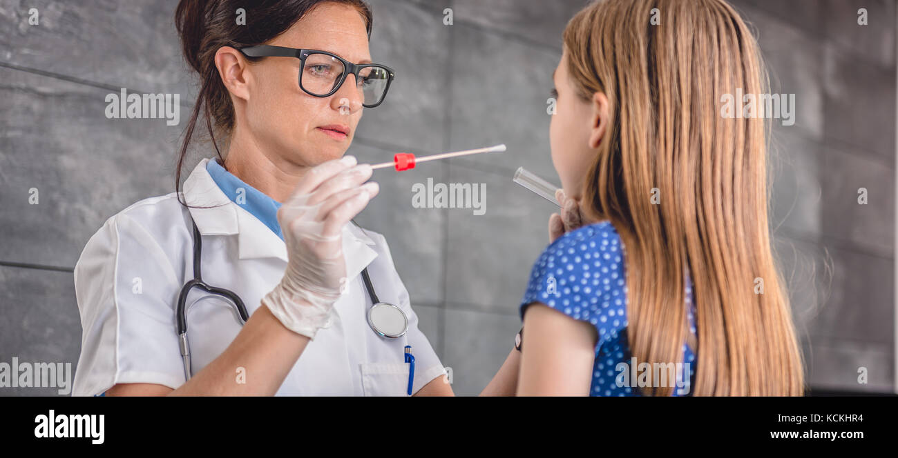 Female pediatrician using a swab to take a sample from a patient's throat Stock Photo