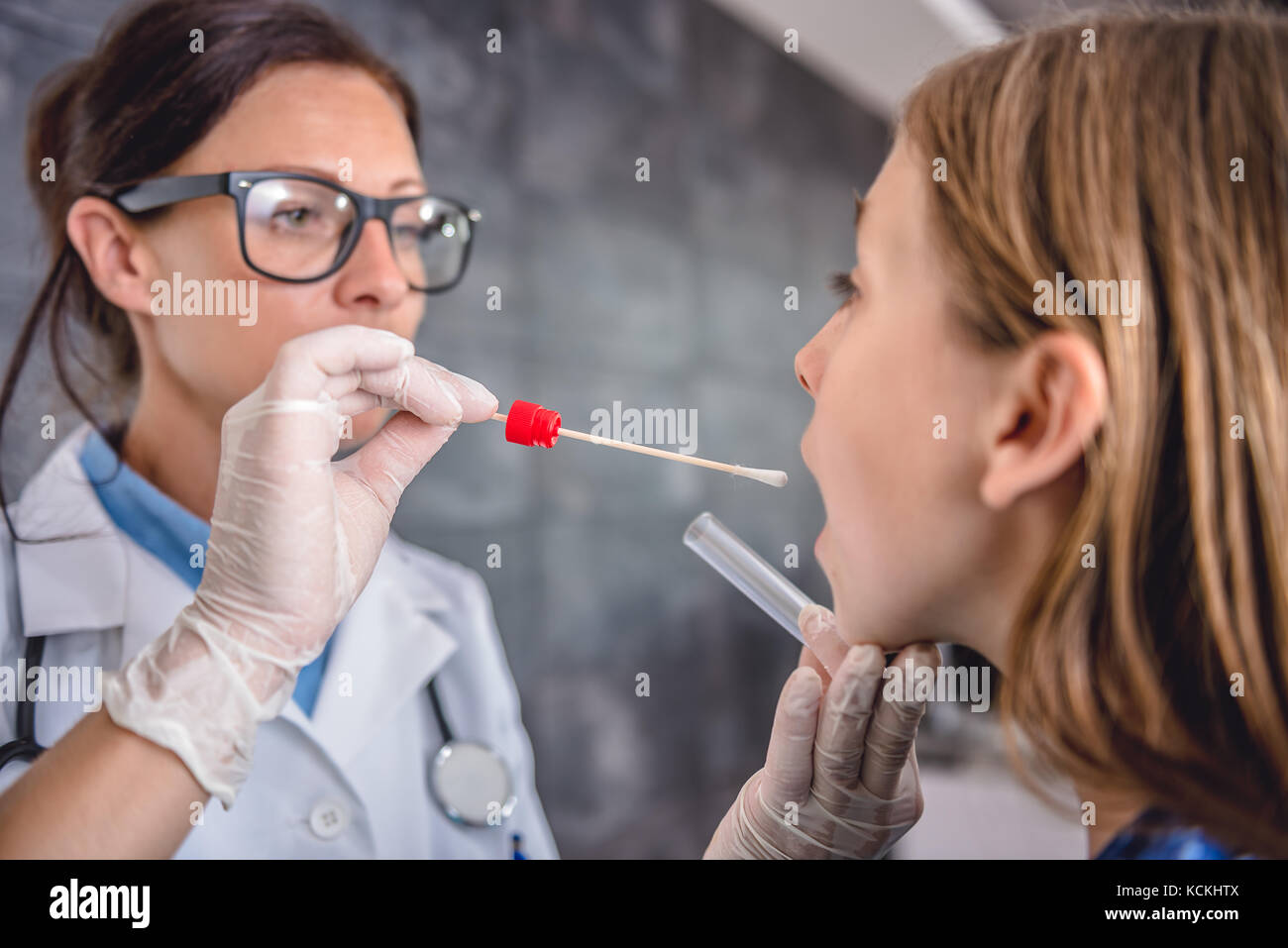 Female pediatrician using a swab to take a sample from a patient's throat Stock Photo