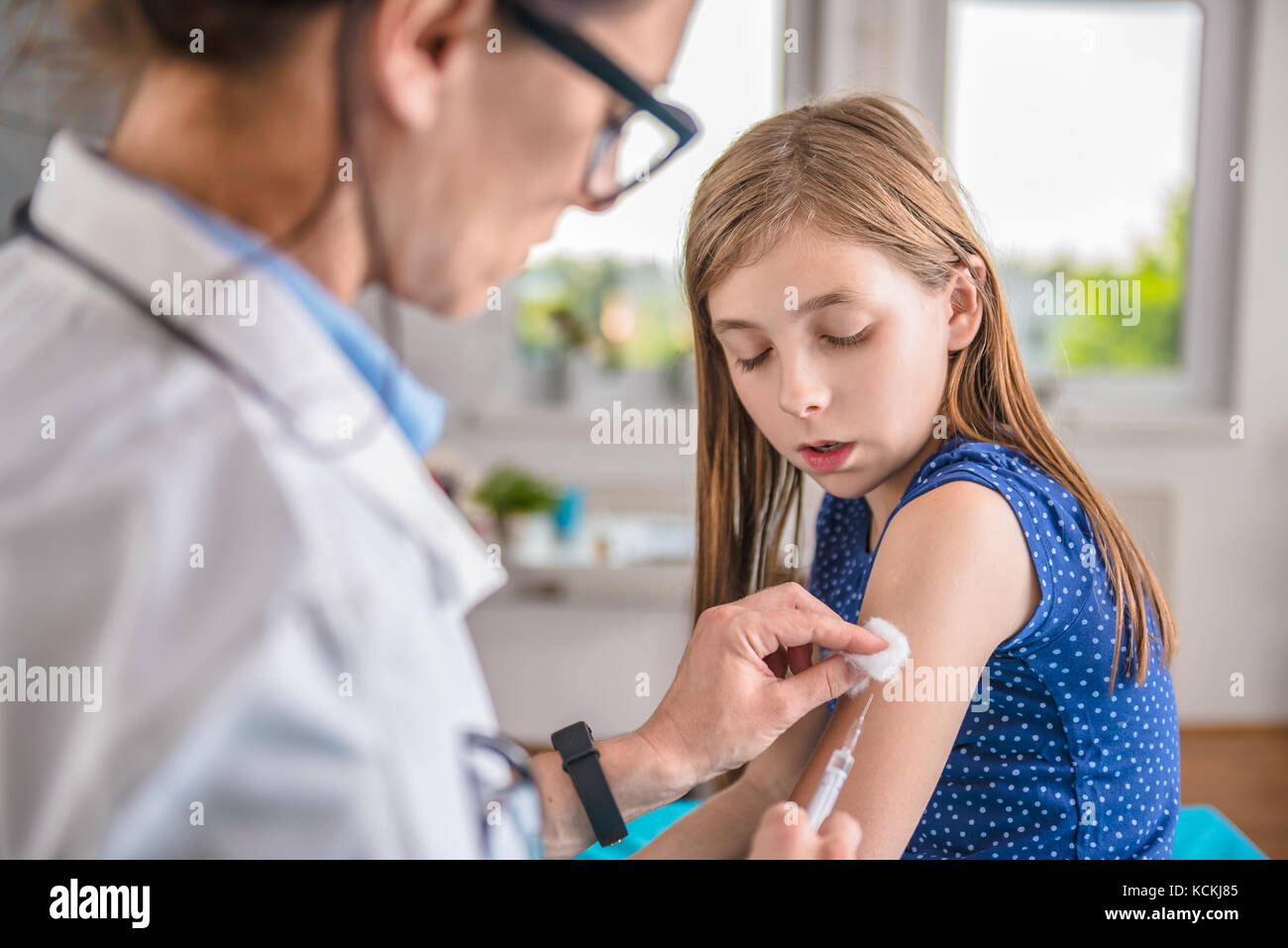 Pediatrics female doctor giving a young girl a vaccine shot in the arm Stock Photo