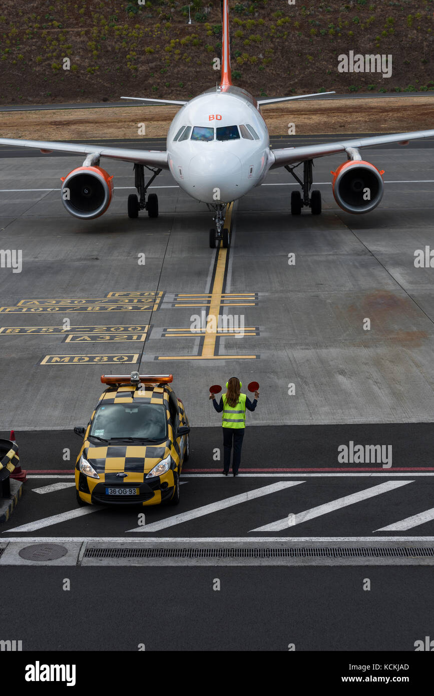 Aircraft marshaller at Cristiano Ronaldo International Airport guides an Easyjet Airbius A319 to its parking stand. Stock Photo