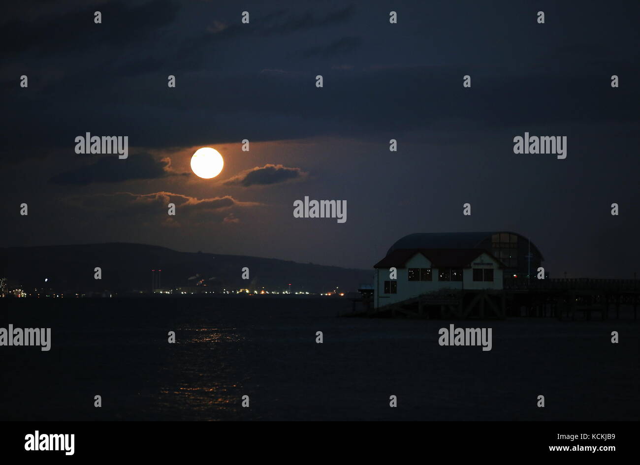 The harvest fool moon rises over Mumbles boathouse near Swansea, Wales, UK. Stock Photo