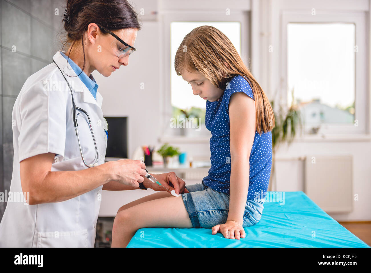 Pediatrics female doctor giving a young girl a vaccine shot in the leg Stock Photo