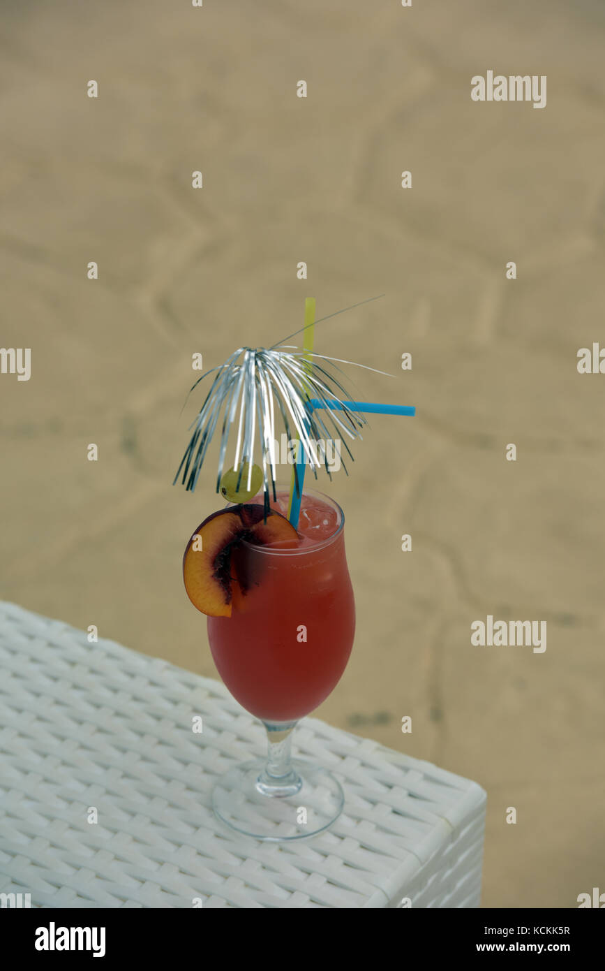 a colourful cocktail with straws and umbrella next to a swimming pool ready for drinking. Stock Photo