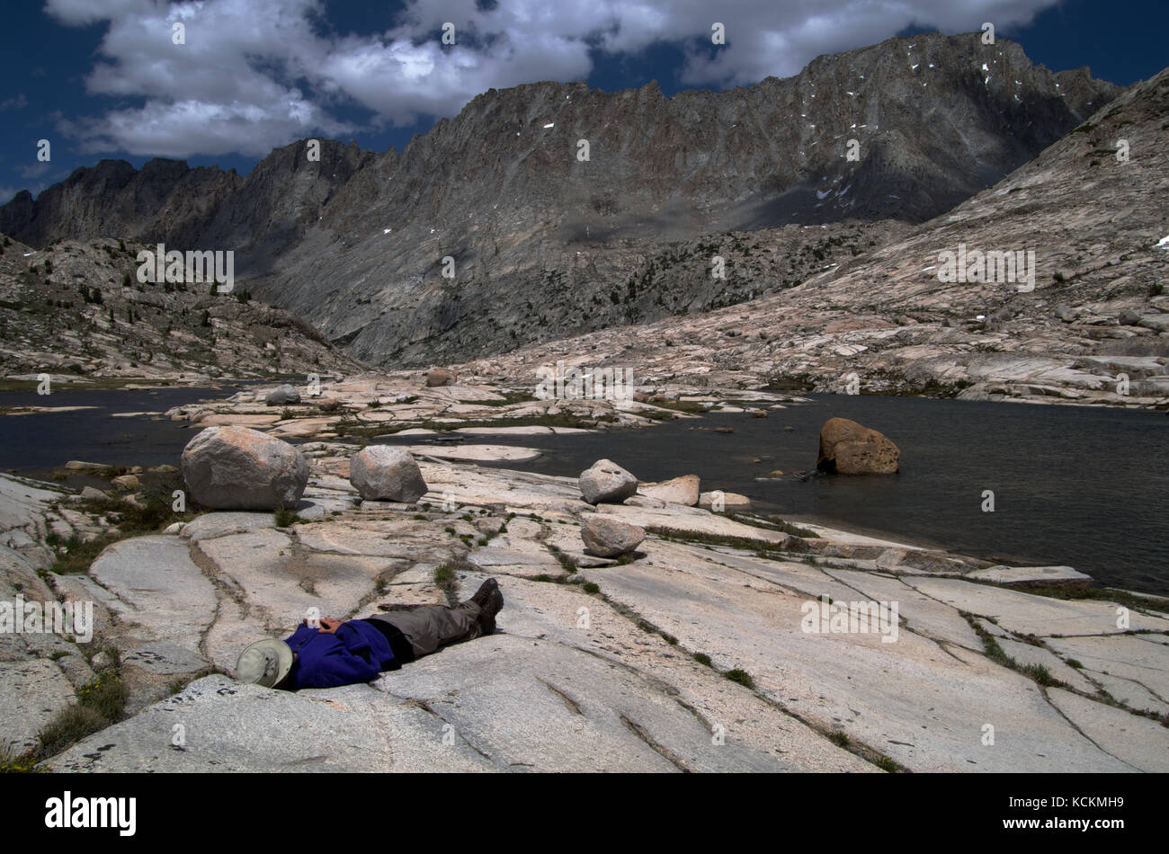Hiker takes a rest stop next to Evolution Creek along the John Muir Trail in the Sierra Nevada California Stock Photo