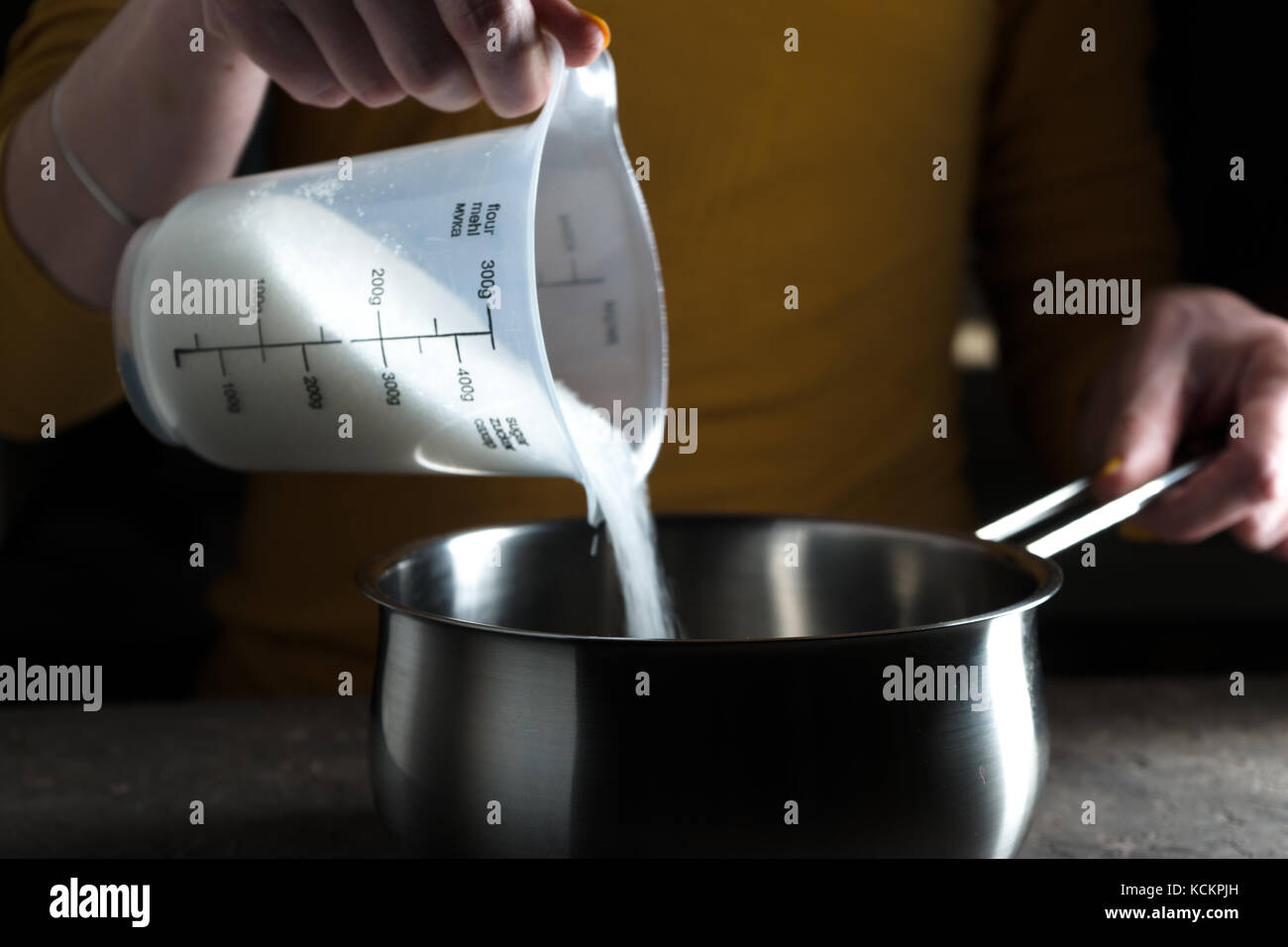 Sugar granulated sugar is poured into the saute pan side view horizontal Stock Photo