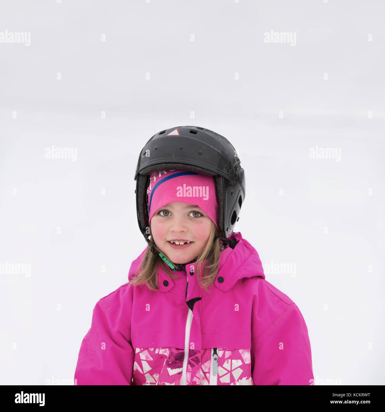 Eye contact portrait of young smiling girl with helmet in the snow outdoors Stock Photo