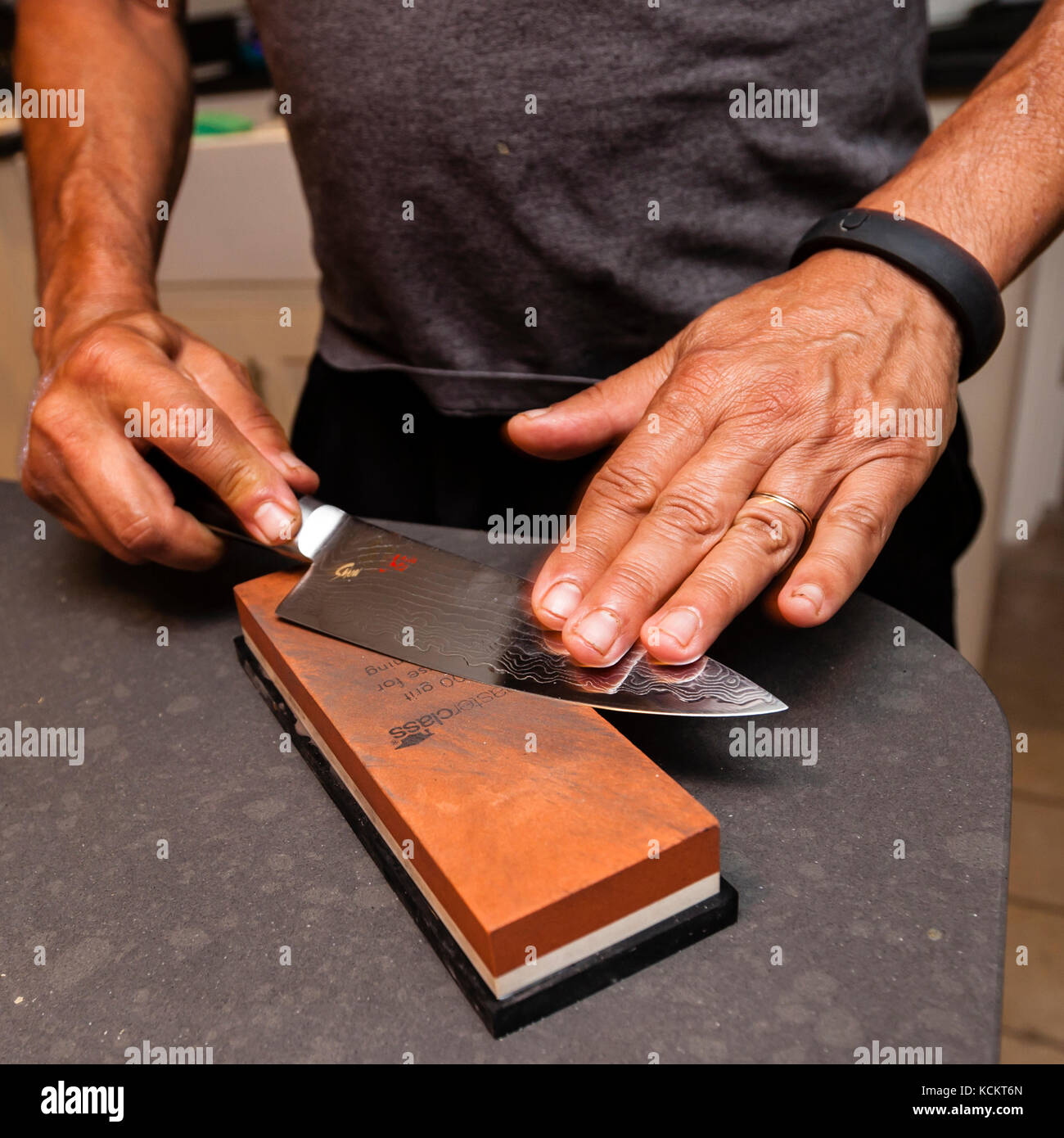 Chinese cook sharpening his Japanese knife before preparing the dishes Stock Photo