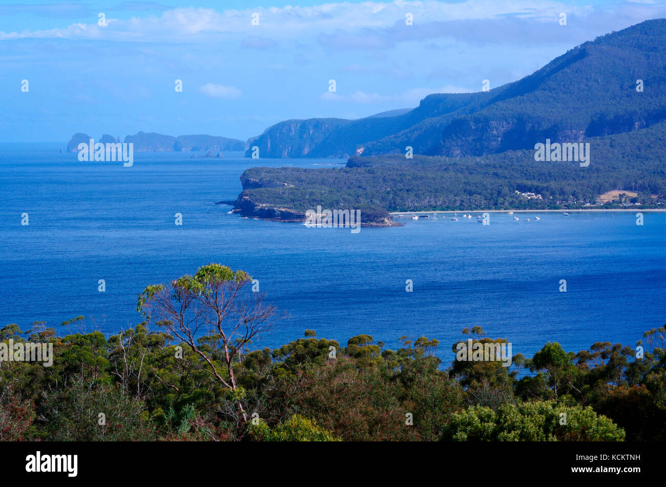 Tasman Peninsula coastline from above Eaglehawk Neck, with Cape Hauy and the two rounded humps of the Lanterns in the distance, and Pirates Bay in the Stock Photo