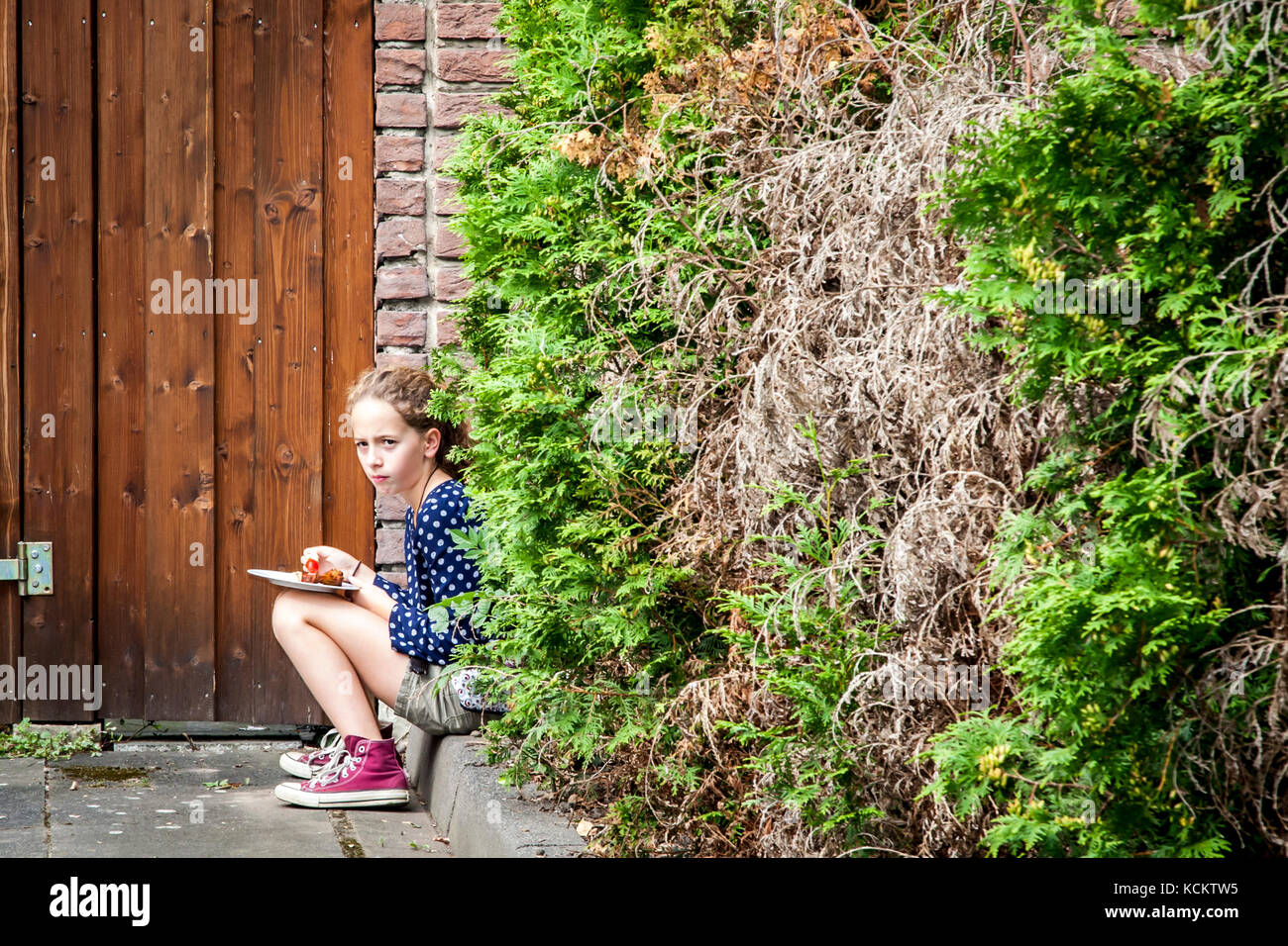 Young Girl hiding to eat food Stock Photo