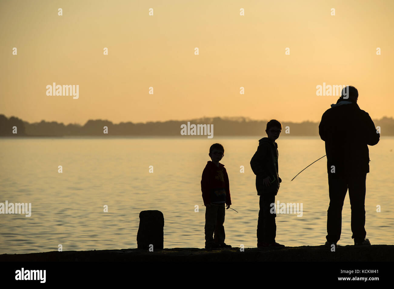 Silhouette of boy fishing at sunset hi-res stock photography and