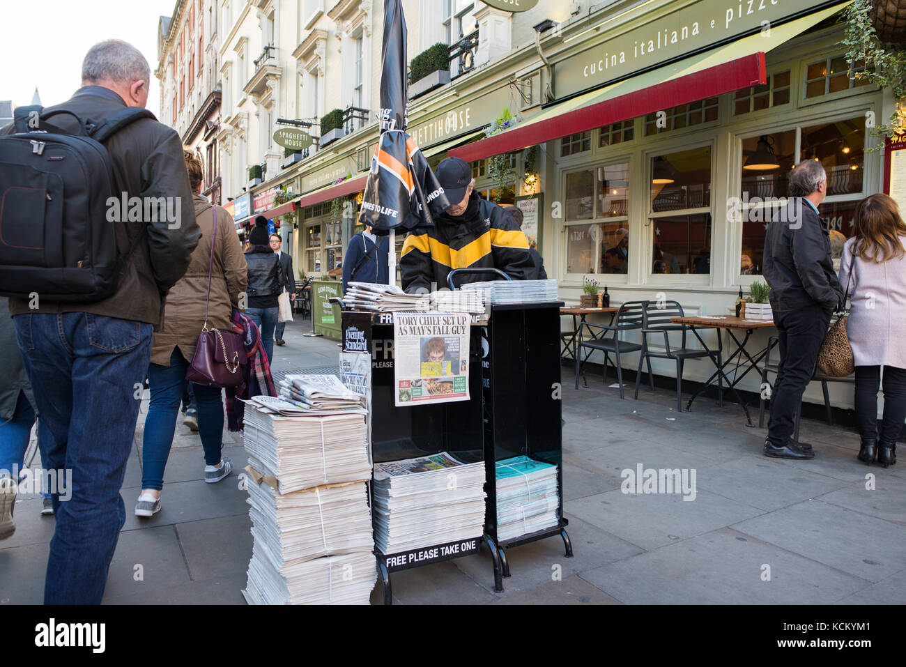 Newspaper vendor distributing free copies of the Evening Standard at a  street stand, London, England, UK Stock Photo