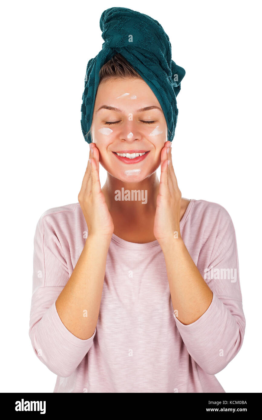 Beautiful young woman after shower with towel on head applying face