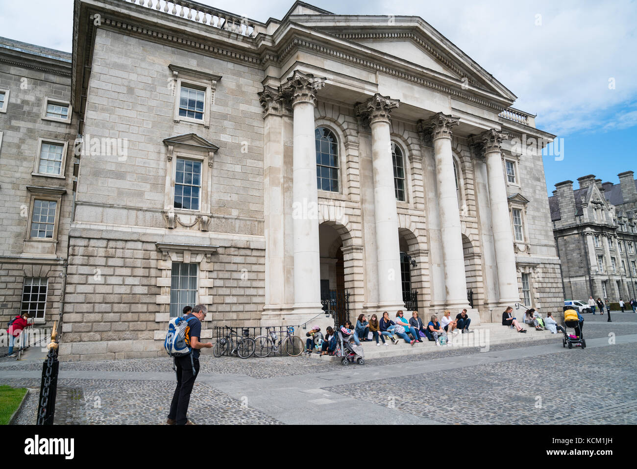 DUBLIN, IRELAND - AUGUST 9, 2017; People sitting on steps of Trinity College Chapel in Parliament Square of College grounds and buildings in Dublin in Stock Photo