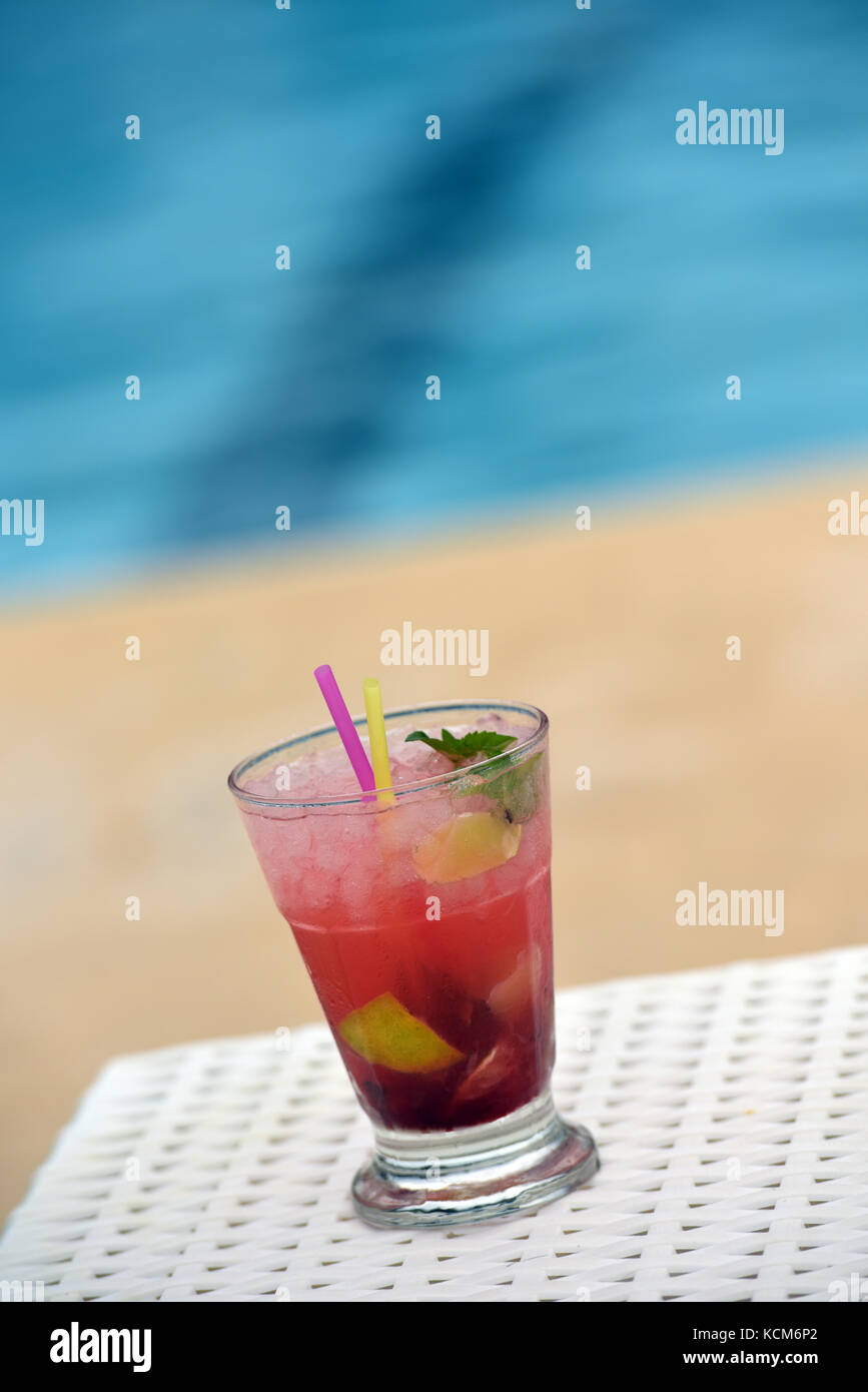 a colourful cocktail with straws and umbrella next to a swimming pool ready for drinking. Stock Photo
