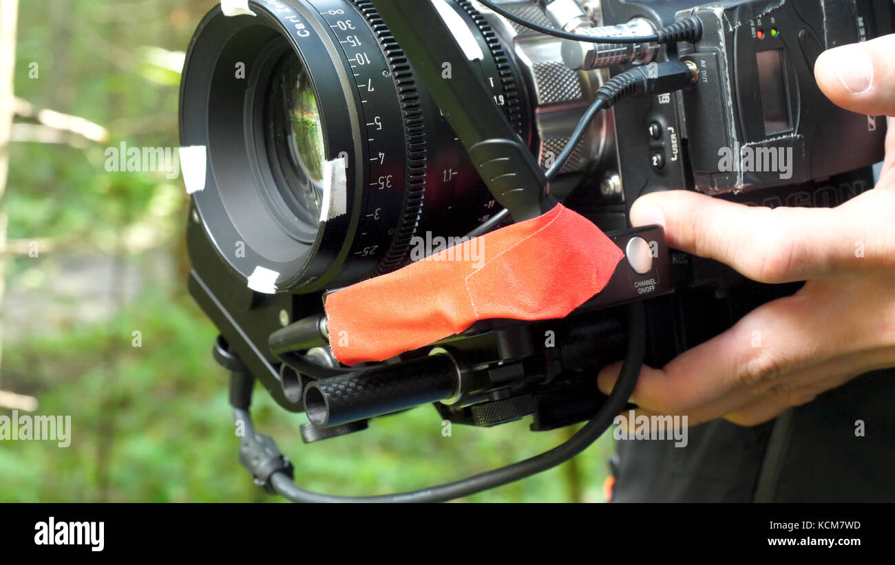 Man holding a camera filming a movie in the forest. Expensive camera