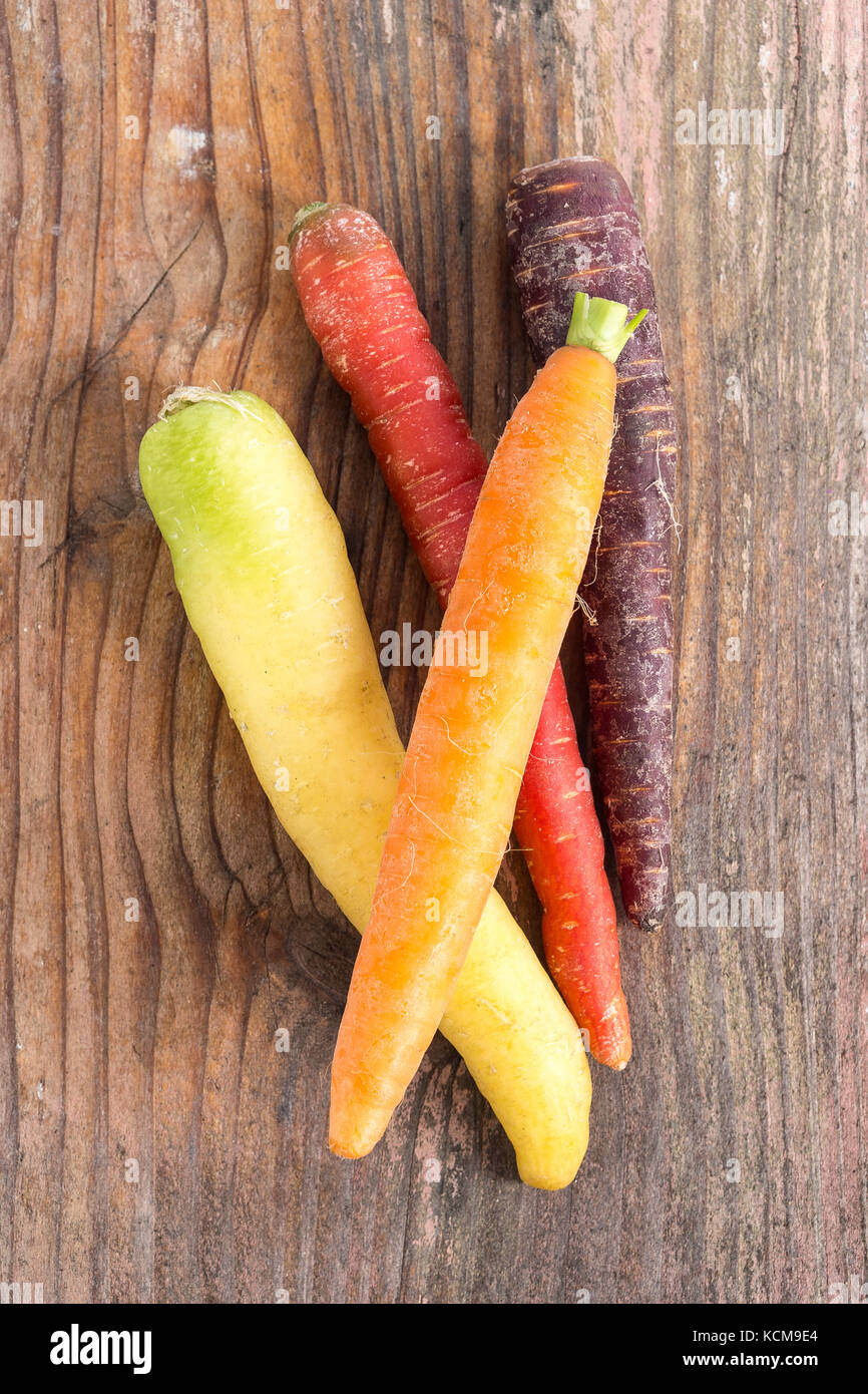 arrangement of heritage carrot varieties against a rustic wooden background Stock Photo