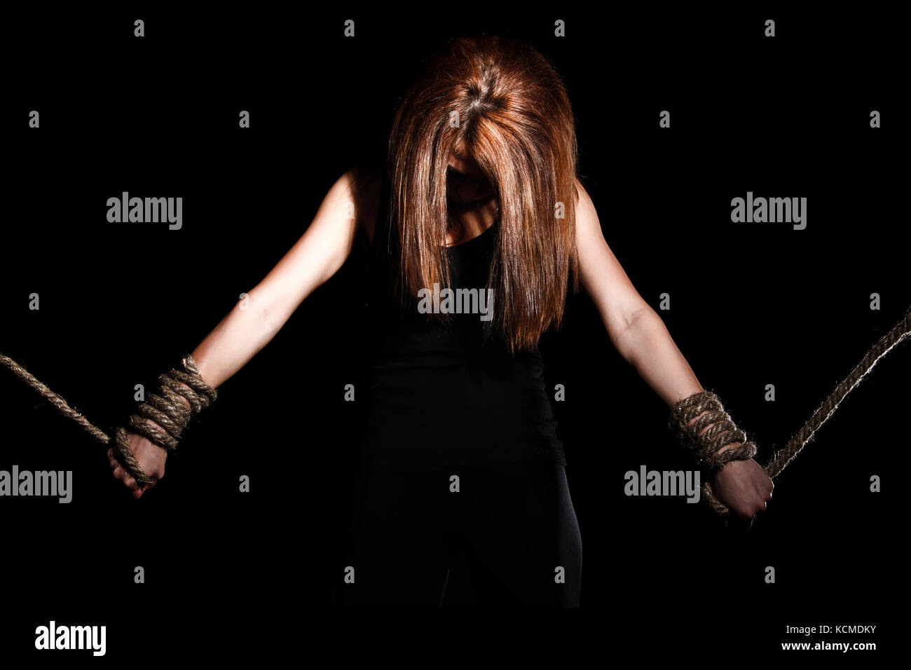 Beautiful young woman with tied arms over black background Stock Photo