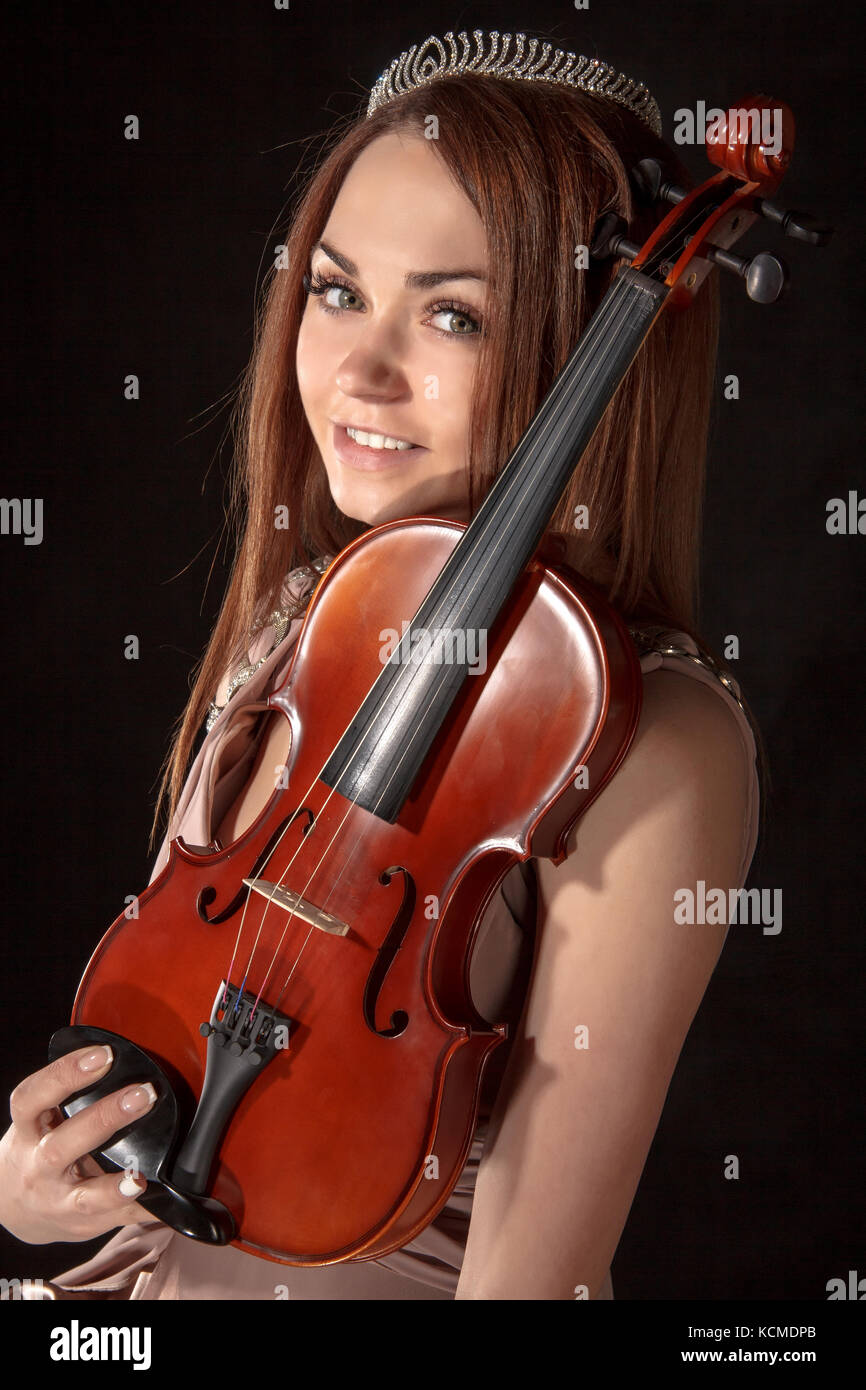 Pretty young woman holding a violin over black background Stock Photo ...