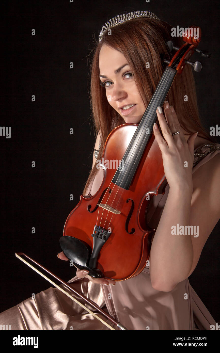 Pretty young woman holding a violin over black background Stock Photo ...