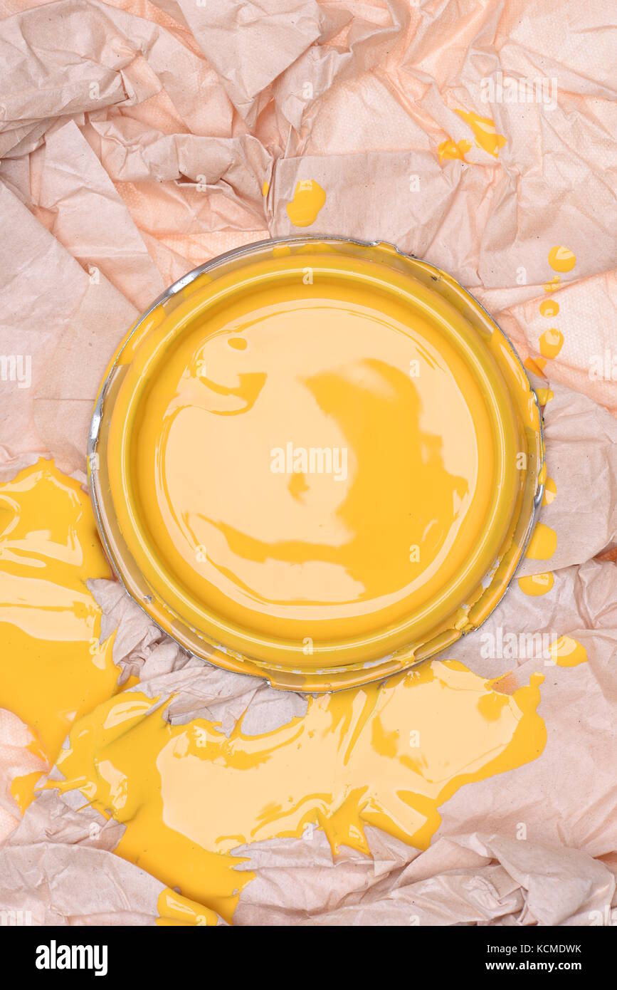 Can lid with yellow paint on crumpled paper, top view Stock Photo