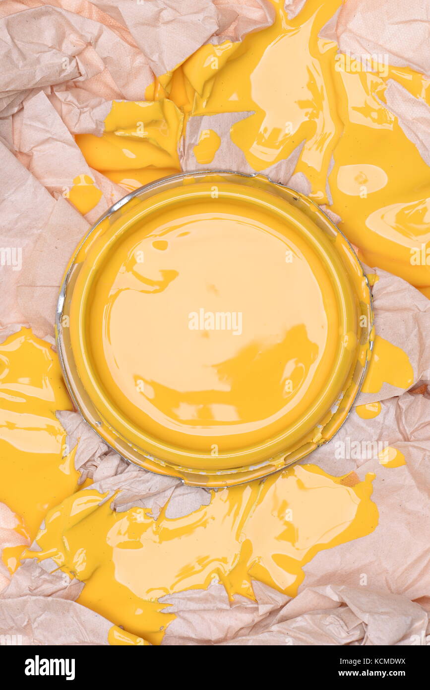 Can lid with yellow paint on crumpled paper, top view Stock Photo