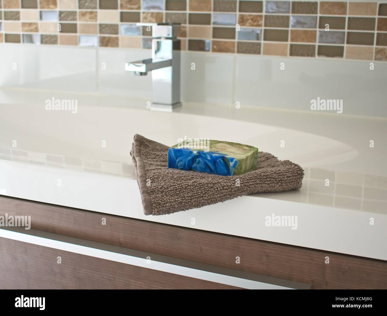 Hand towel and soap on basin with mixer tap in the background Stock Photo