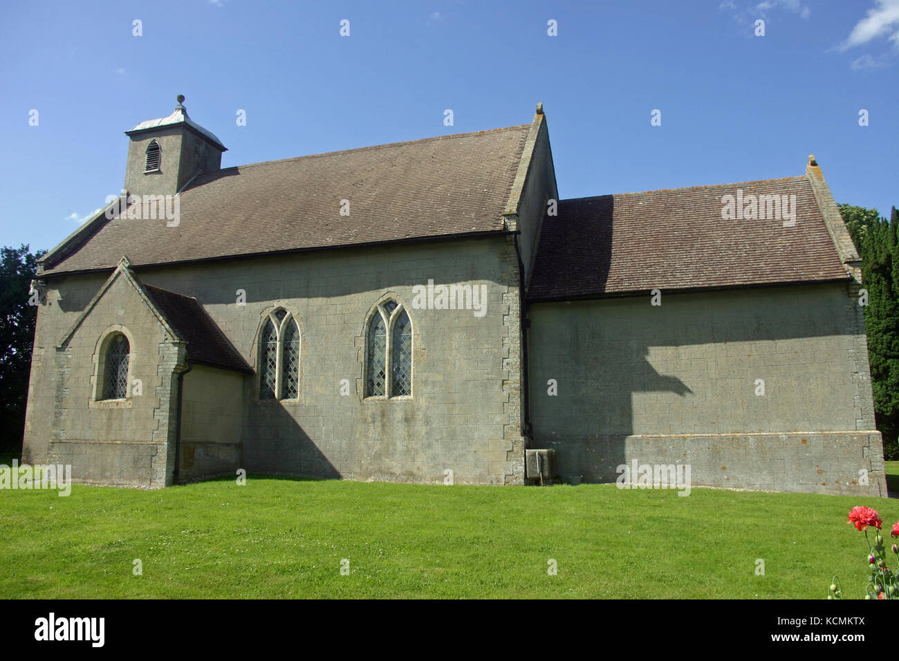 King Charles the Martyr church in Shelland, Suffolk. Viewed from the south. Mown grass in the foreground. Trees and blue sky with white cloud in the b Stock Photo