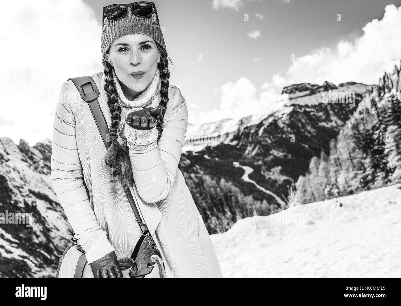 Winter on higher level of fun. happy elegant traveller woman in the front of mountain scenery in Alto Adige, Italy blowing air kiss Stock Photo
