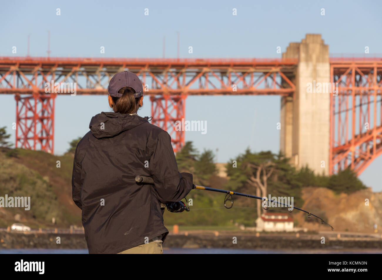 Rear view of a man fishing at Torpedo wharf Crissy Field vey early in the morning, Golden Gate Bridge, San Francisco. Stock Photo