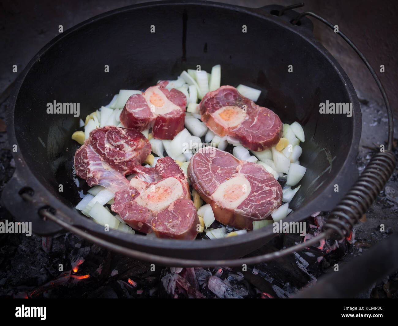 Onions and fresh beef meat cooking over wood fire in cast iron pot or potjiekos, Botswana, Southern Africa Stock Photo