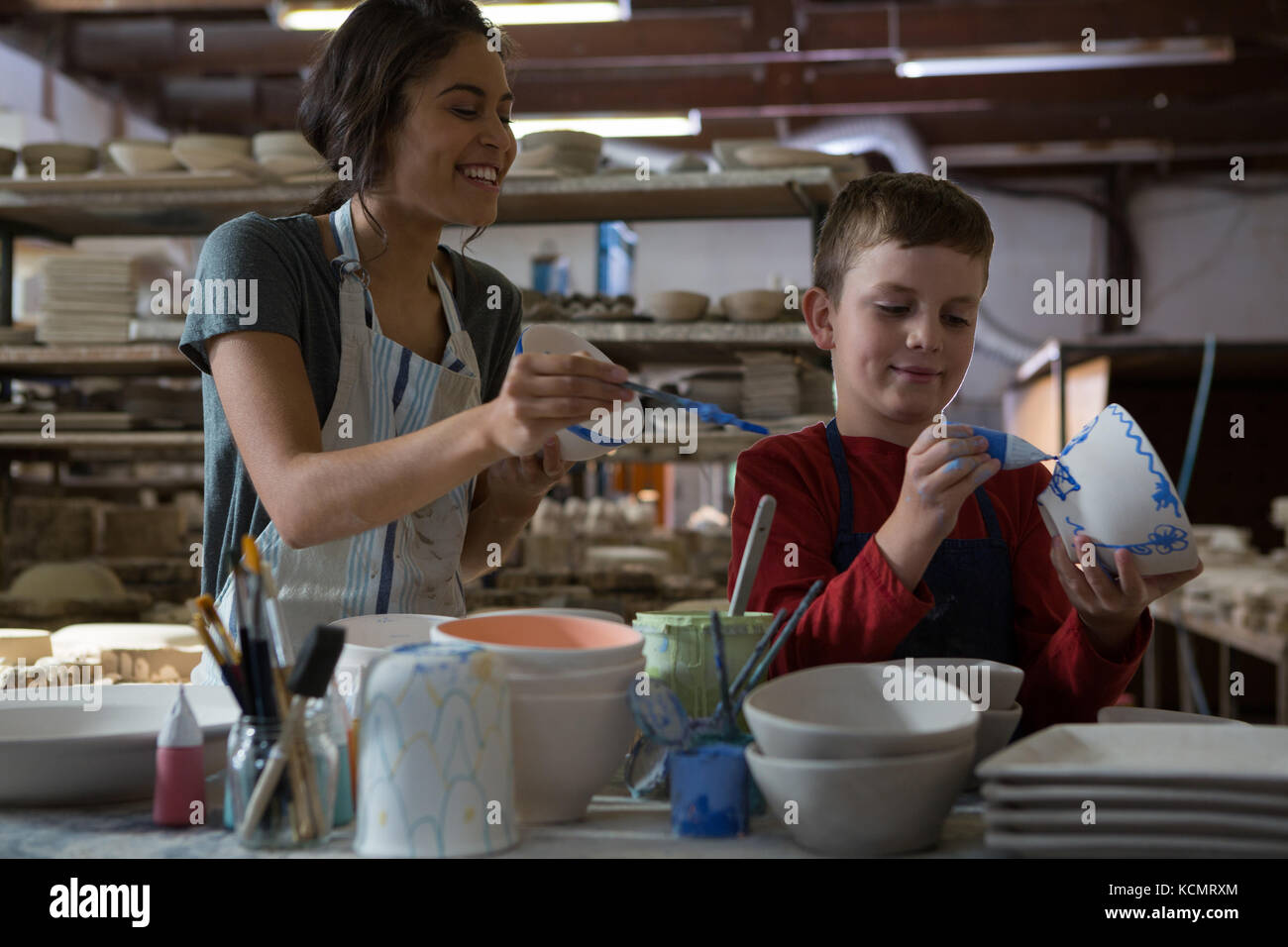 Female potter and boy painting bowl in pottery workshop Stock Photo - Alamy