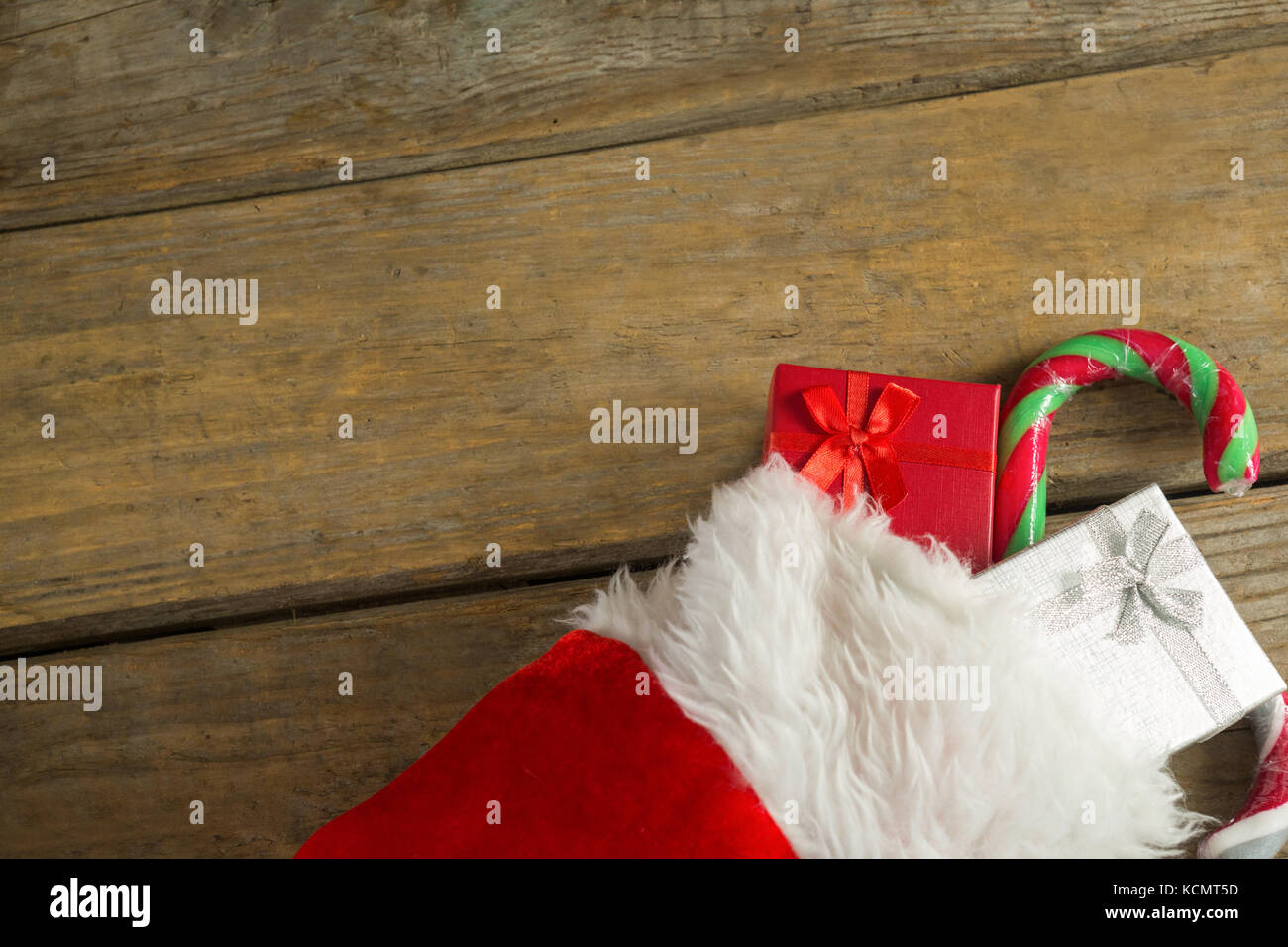 Wrapped gift box and candy cane in stocking against wooden wall during ...
