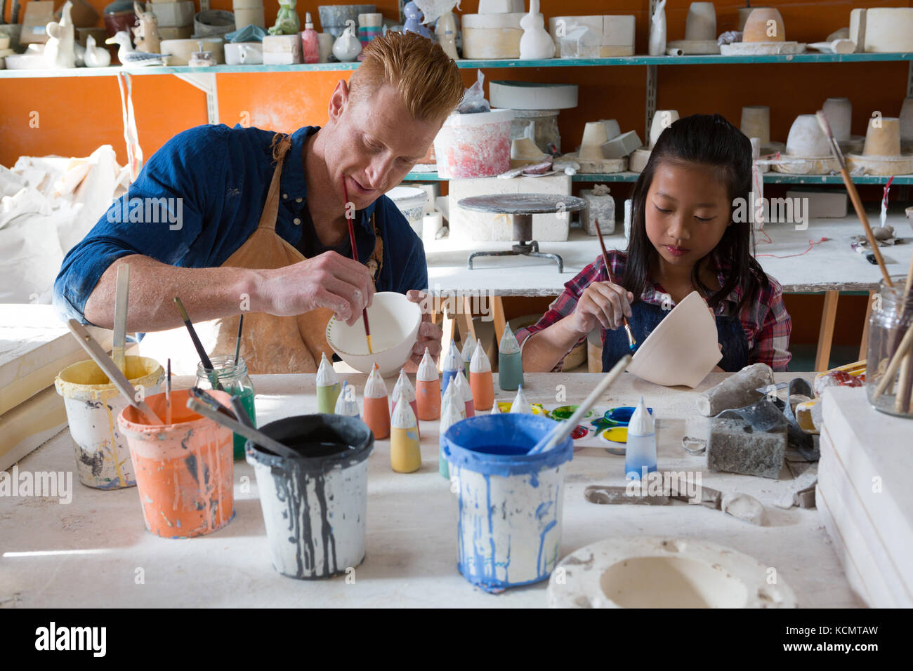 Male potter and girl painting bowl in pottery workshop Stock Photo - Alamy