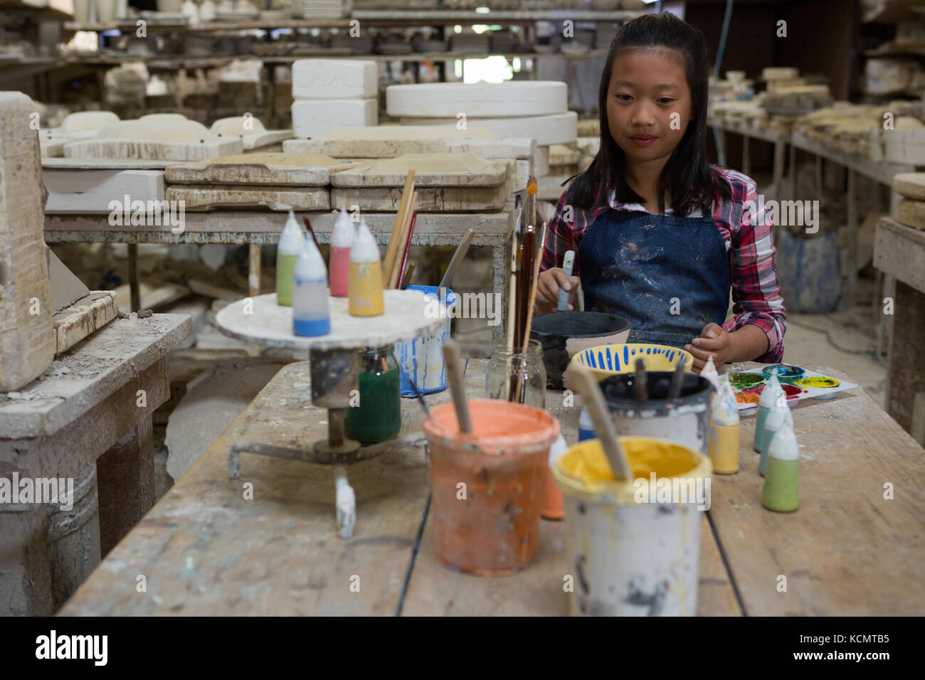 Portrait of girl painting bowl in pottery workshop Stock Photo - Alamy