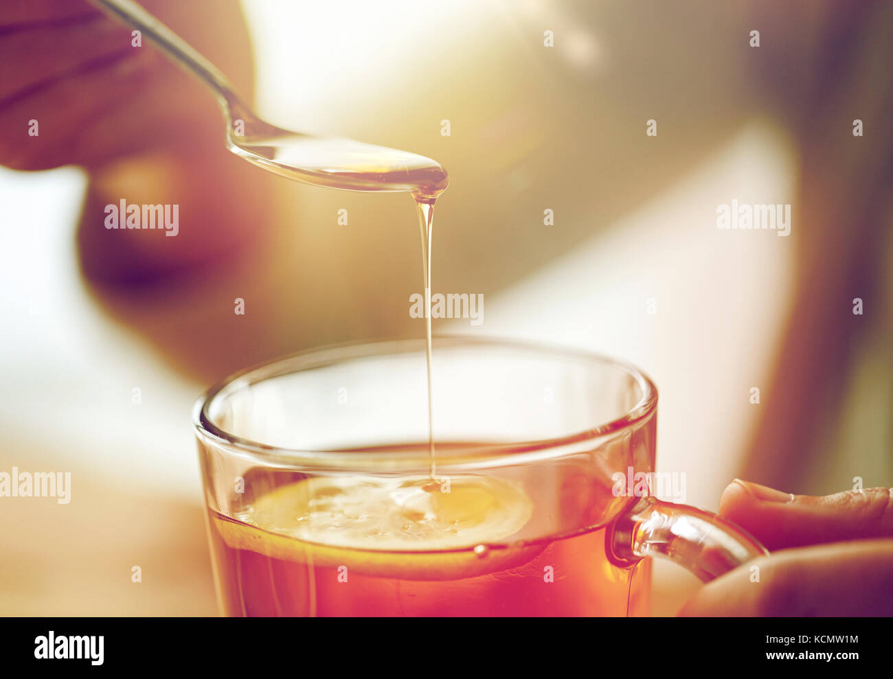 Close up of woman adding honey to tea with lemon stock photo alamy