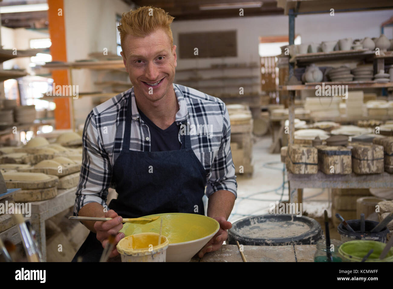 Portrait of male potter painting a bowl in pottery workshop Stock Photo ...