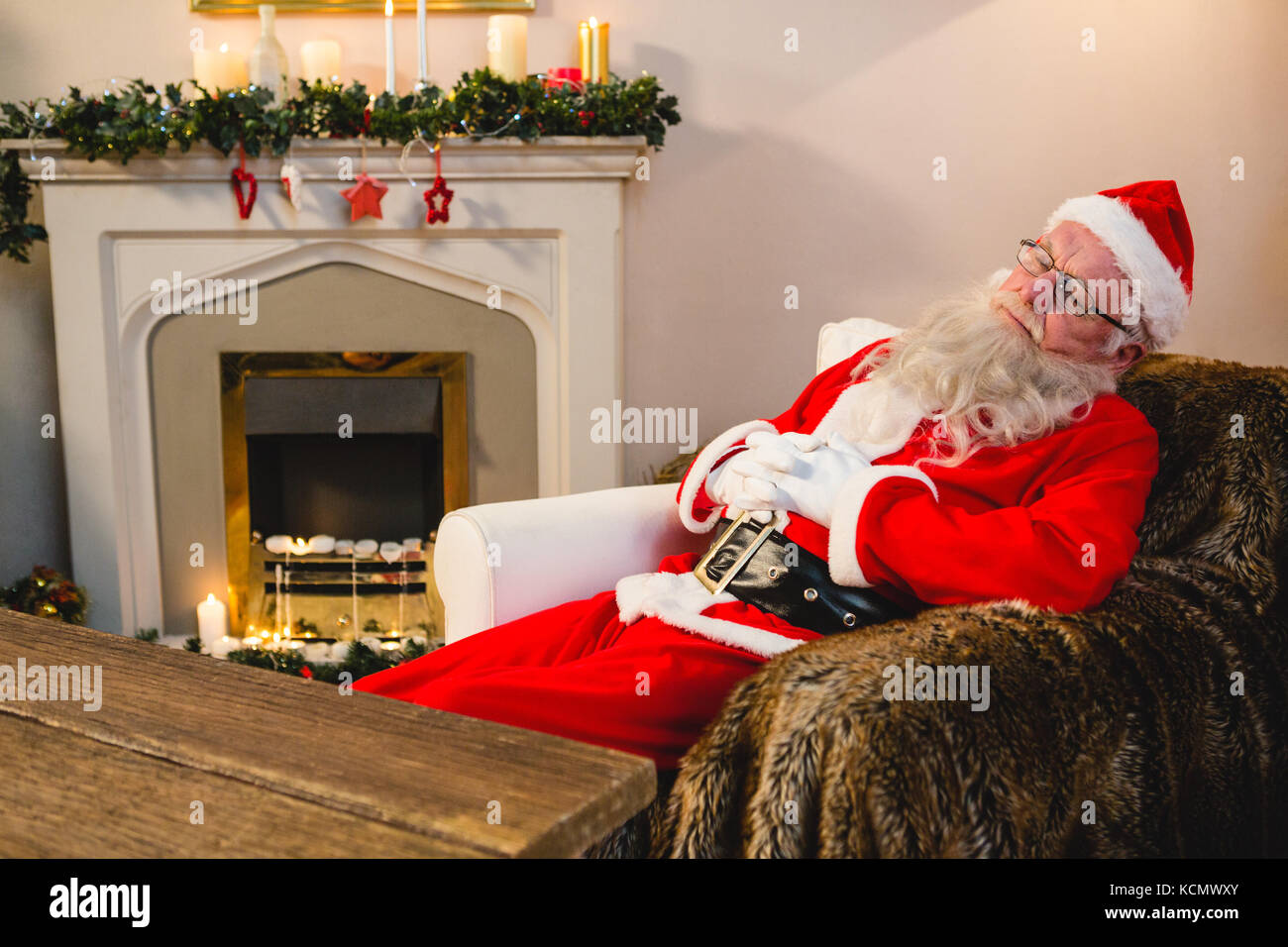 Santa claus relaxing on sofa in living room at home during christmas