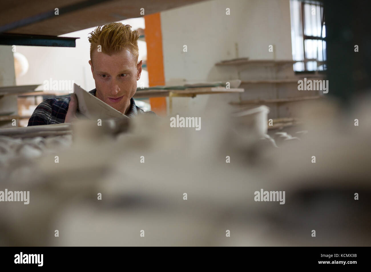 Male potter examining a bowl in pottery workshop Stock Photo - Alamy