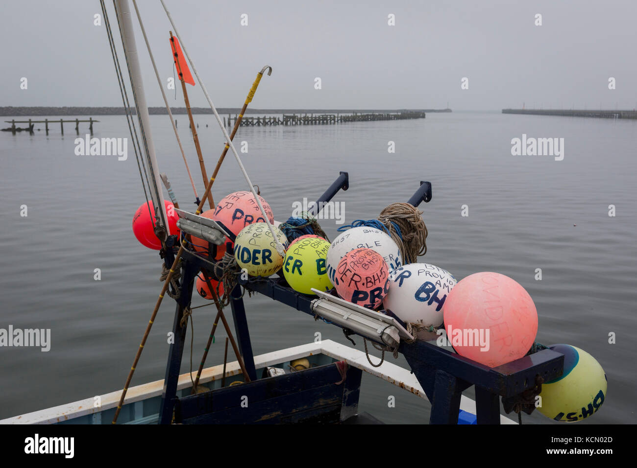 Fishing buoys are attached to the rear of a boat moored in the harbour