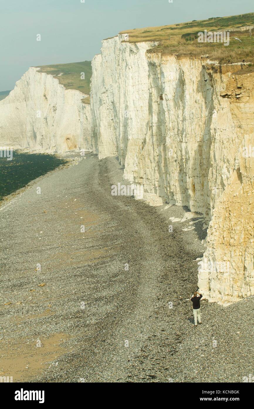 Person photographing chalk cliffs near Beachy Head for scale. Cliffs formed in the