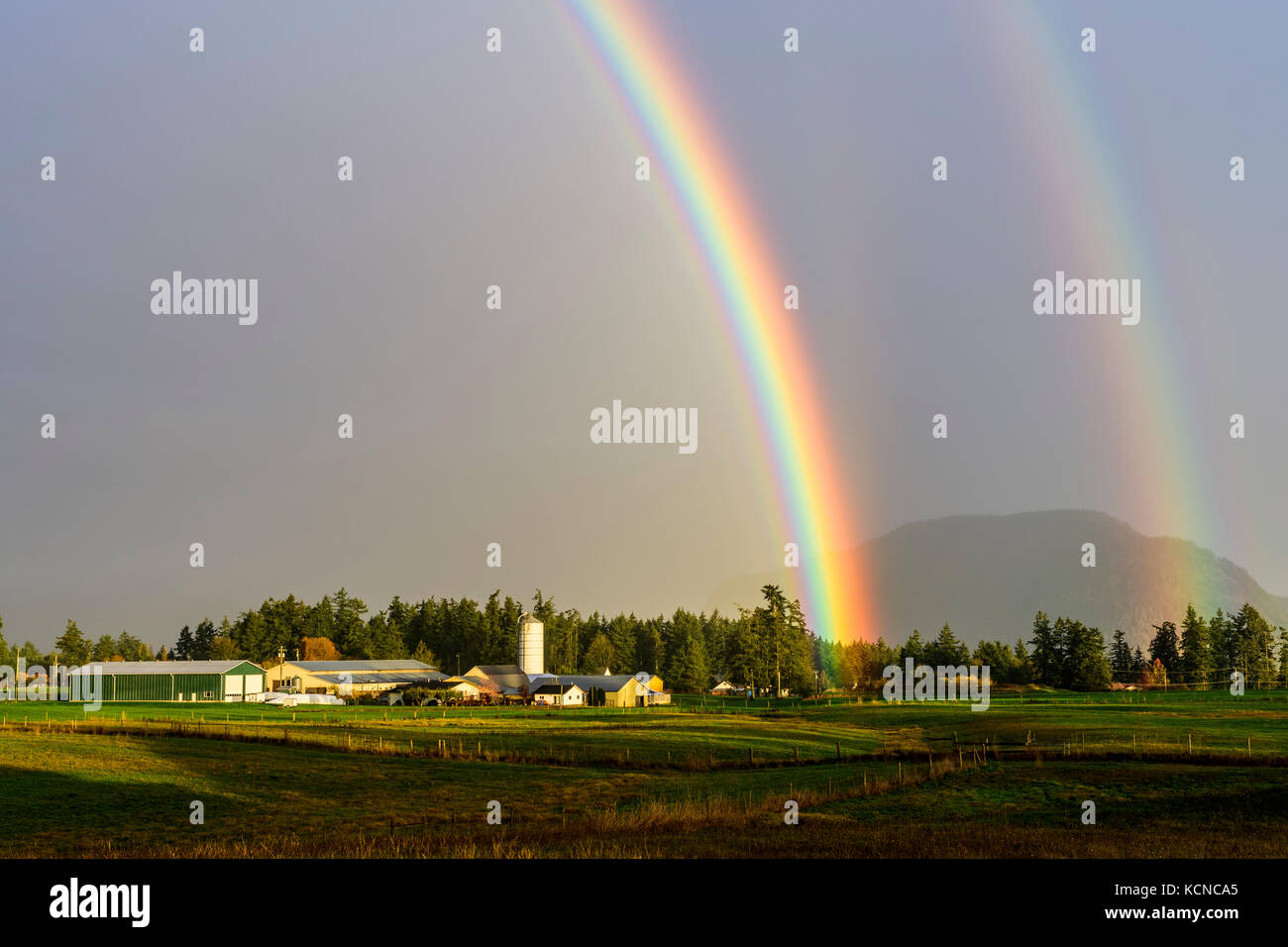 A double rainbow over a farm in Cowichan Bay, British Columbia. Stock Photo