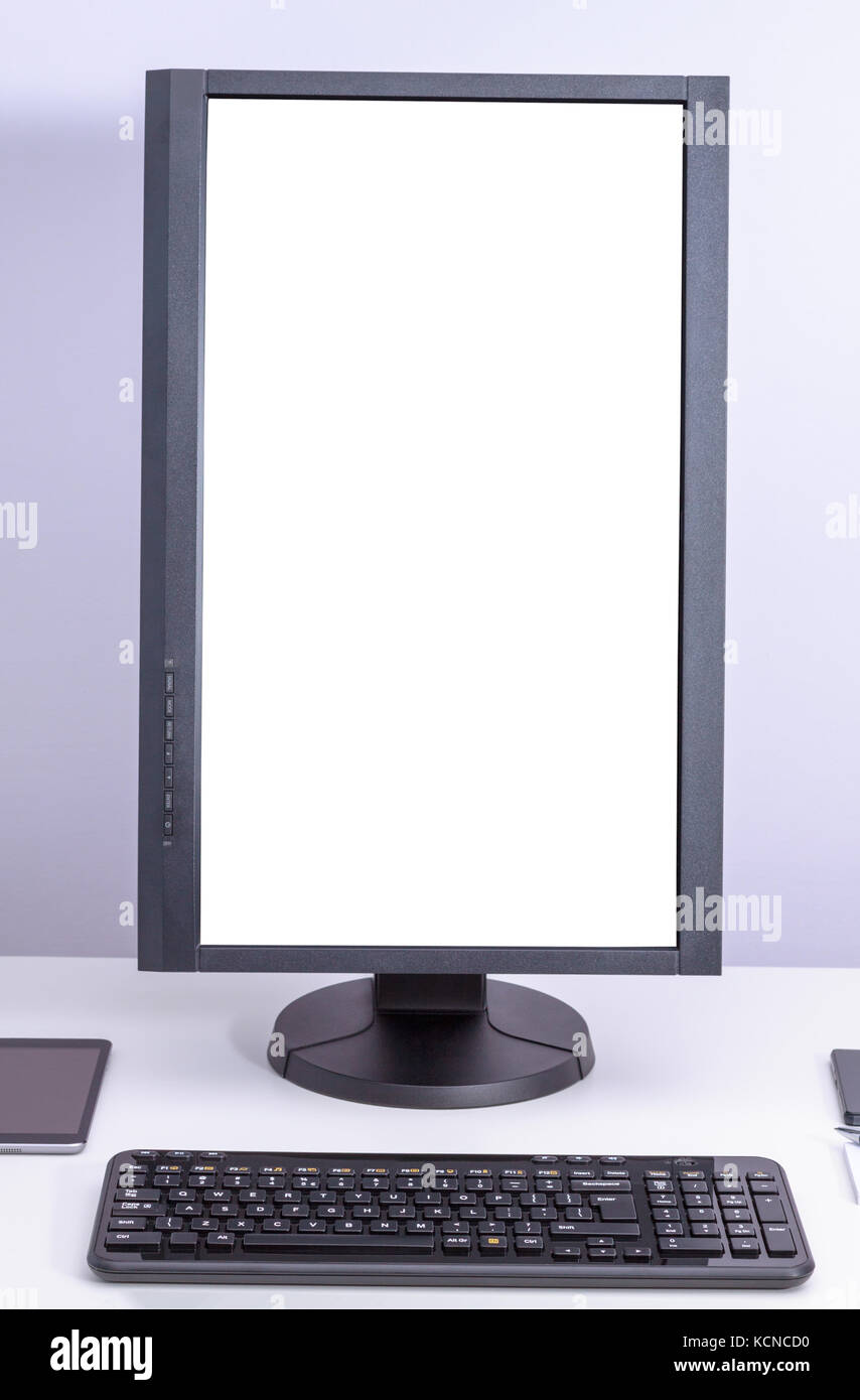 White blank pc monitor turned vertical and keyboard on desk Stock Photo
